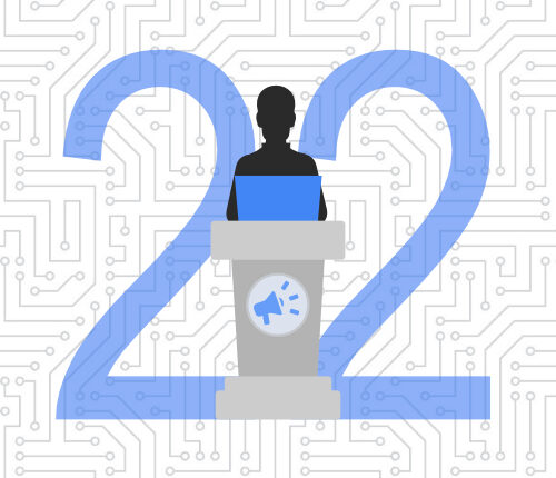 Developer on laptop at a podium decorated with a speakerphone sign in front of the number 22