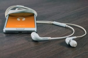 Mobile phone with headphones wrapped around displaying podcast icon